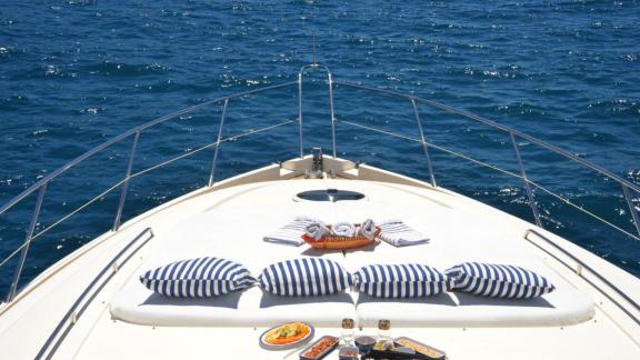 Entspannungsbereich mit Kissen und Snacks auf der Motoryacht Act mit Blick auf das Meer.